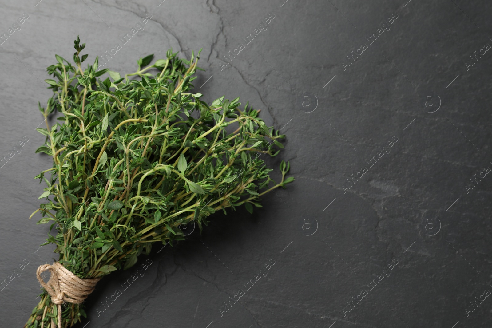 Photo of Bunch of aromatic thyme on black table, top view. Space for text