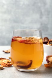 Delicious compote with dried apple slices in glass on grey table