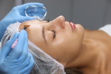 Photo of Cosmetologist applying chemical peel product on client's face in salon