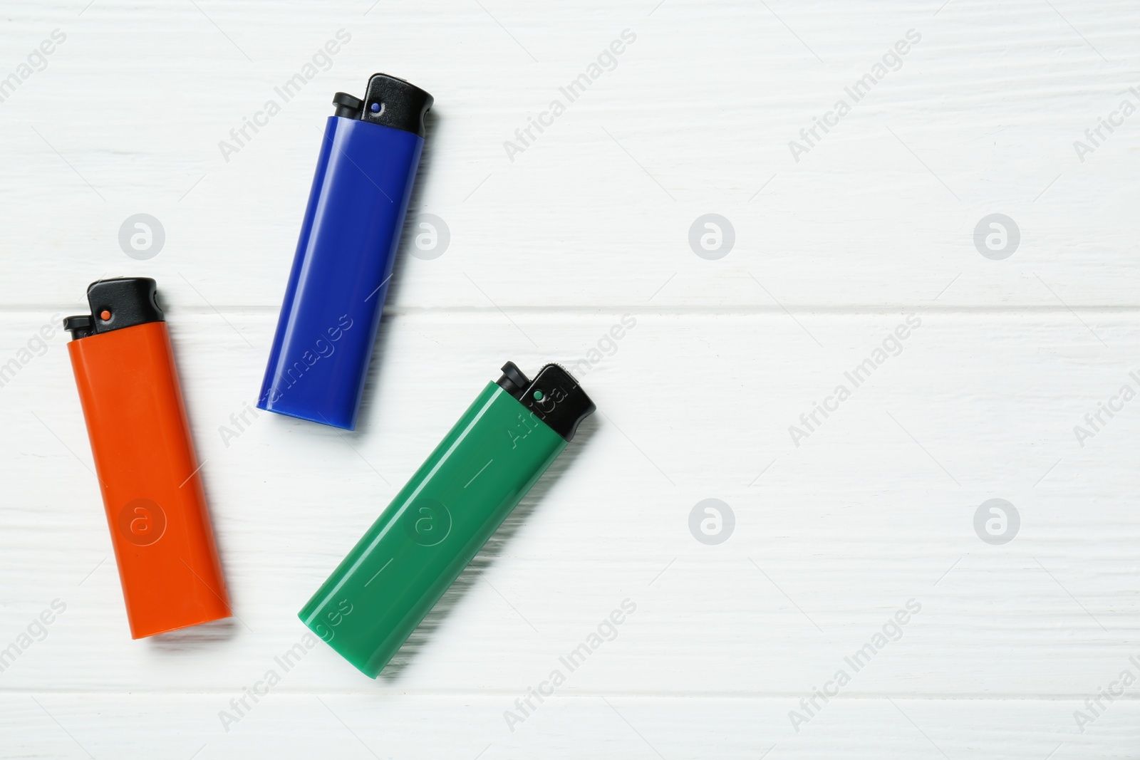 Photo of Stylish small pocket lighters on white wooden background, flat lay. Space for text