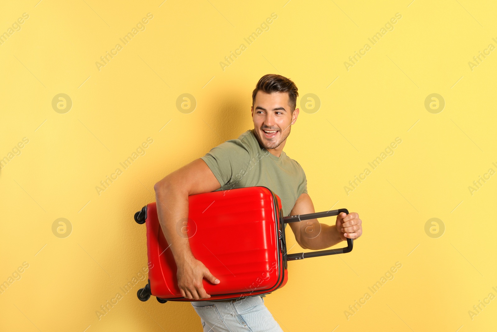 Photo of Young man running with suitcase on color background