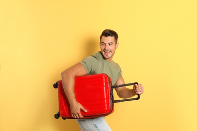 Photo of Young man running with suitcase on color background