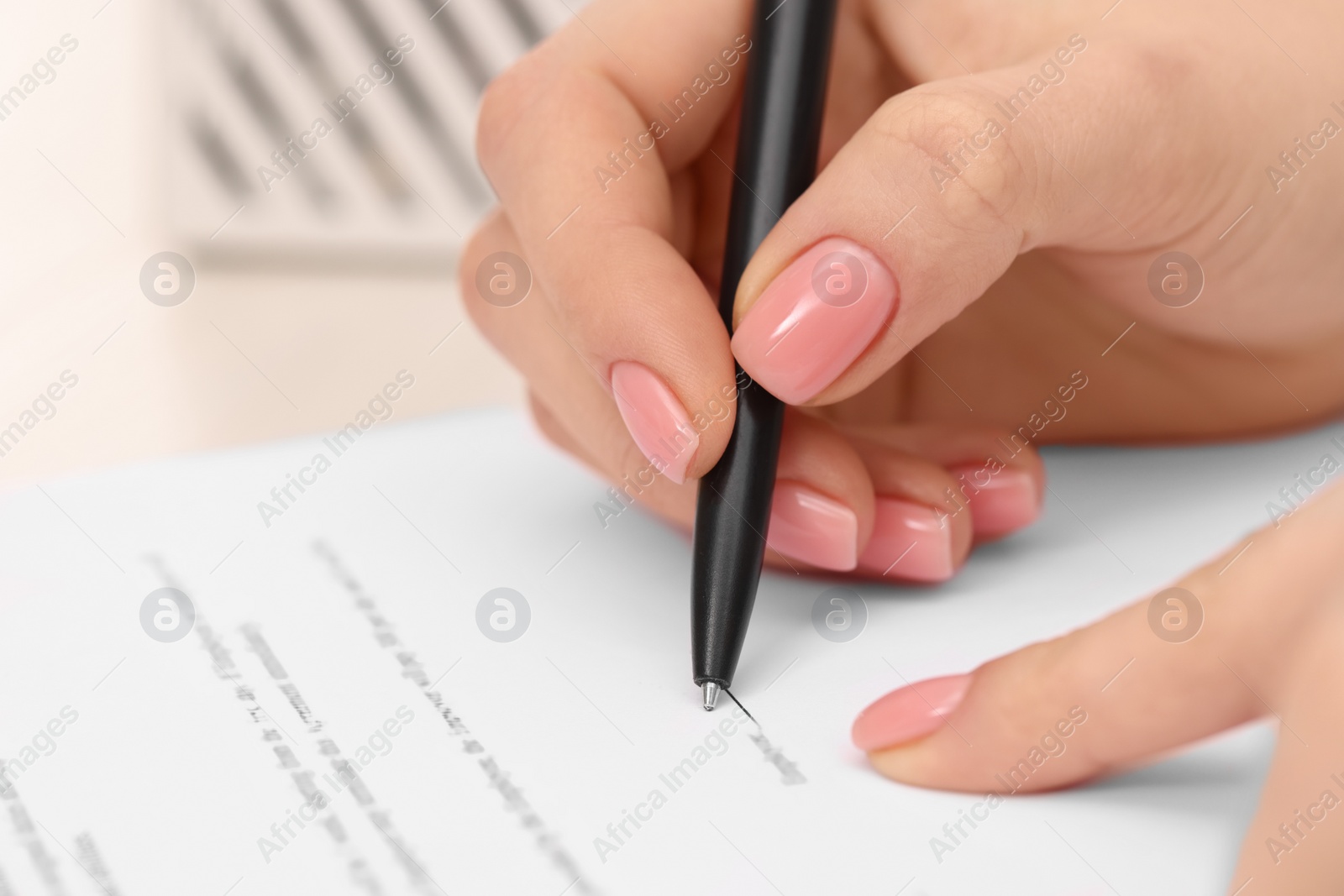 Photo of Woman signing document with pen, closeup view