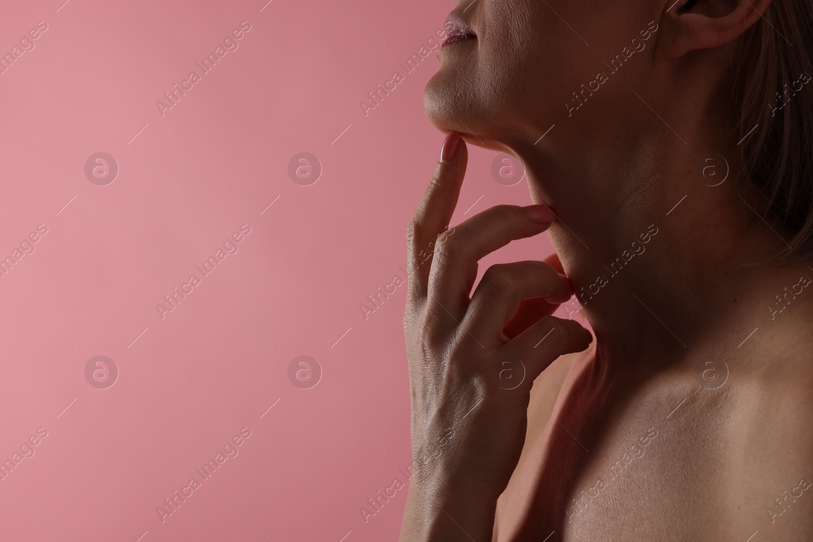 Photo of Woman touching her neck on pink background, closeup. Space for text