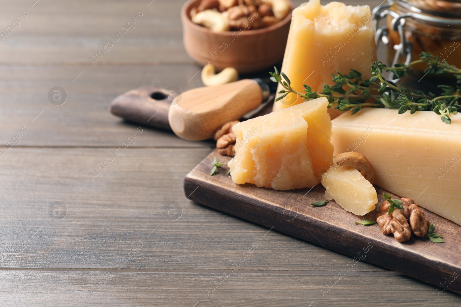 Photo of Delicious parmesan cheese served with honey, walnuts and thyme on wooden table, closeup. Space for text