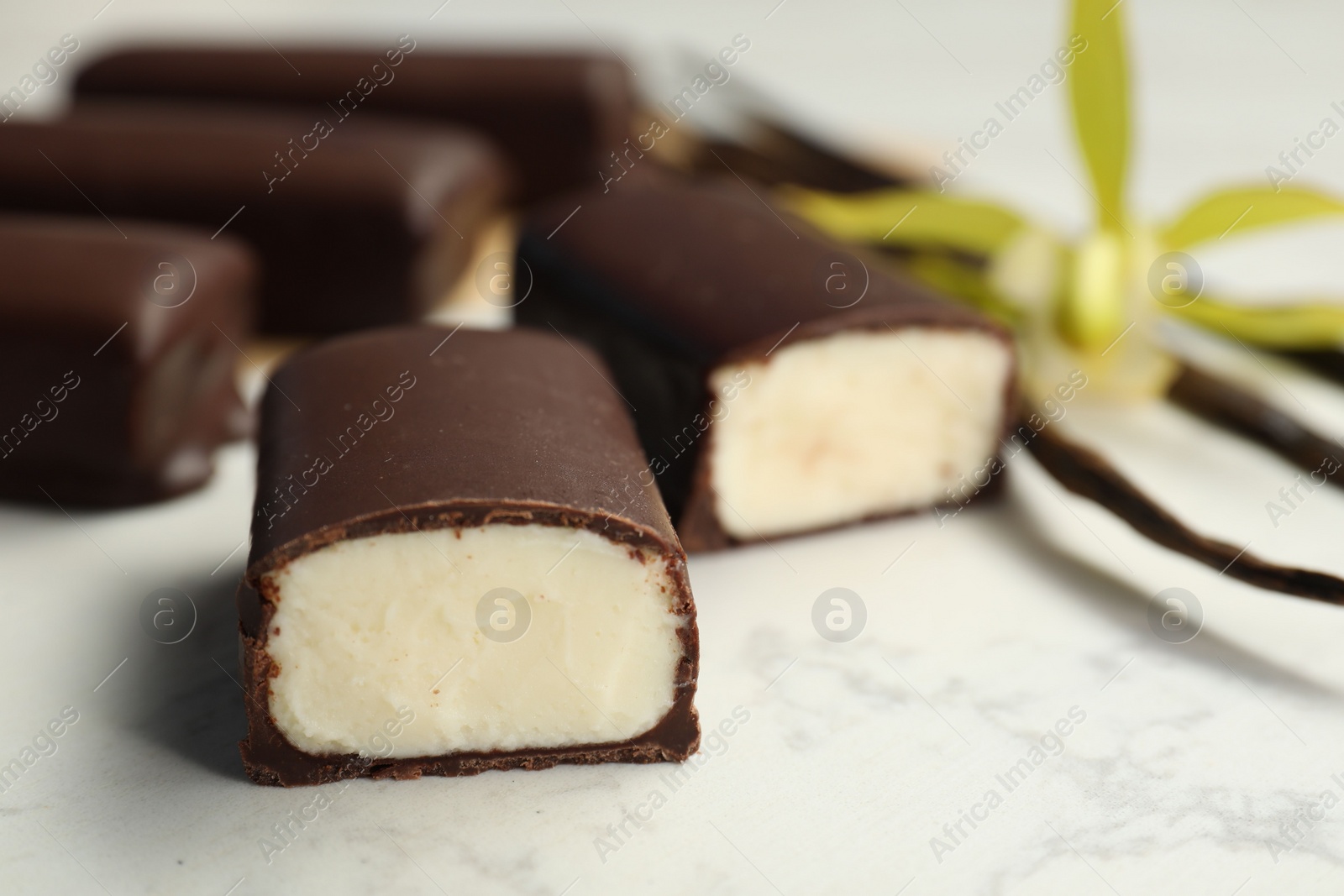 Photo of Glazed vanilla curd cheese bars on white table, closeup