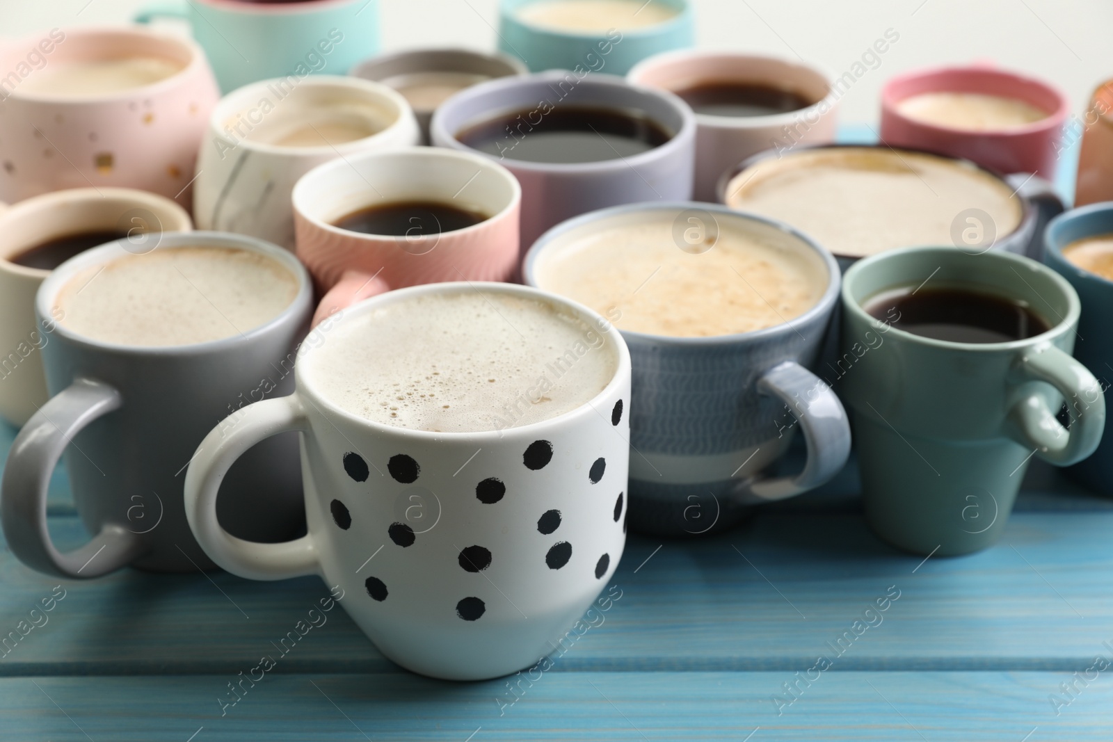 Photo of Many cups of different coffee drinks on light blue wooden table