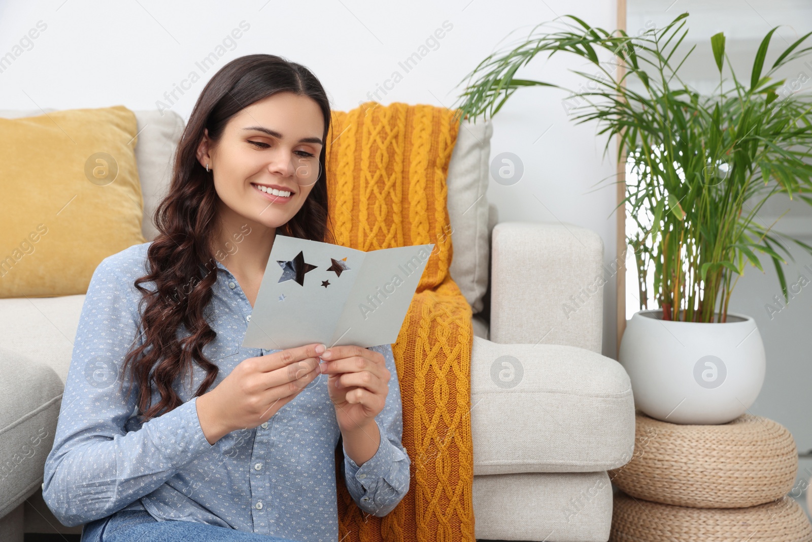 Photo of Young woman with greeting card on floor in living room