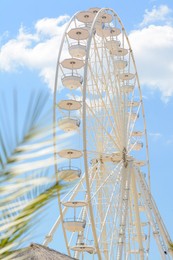 Large white observation wheel against blue cloudy sky