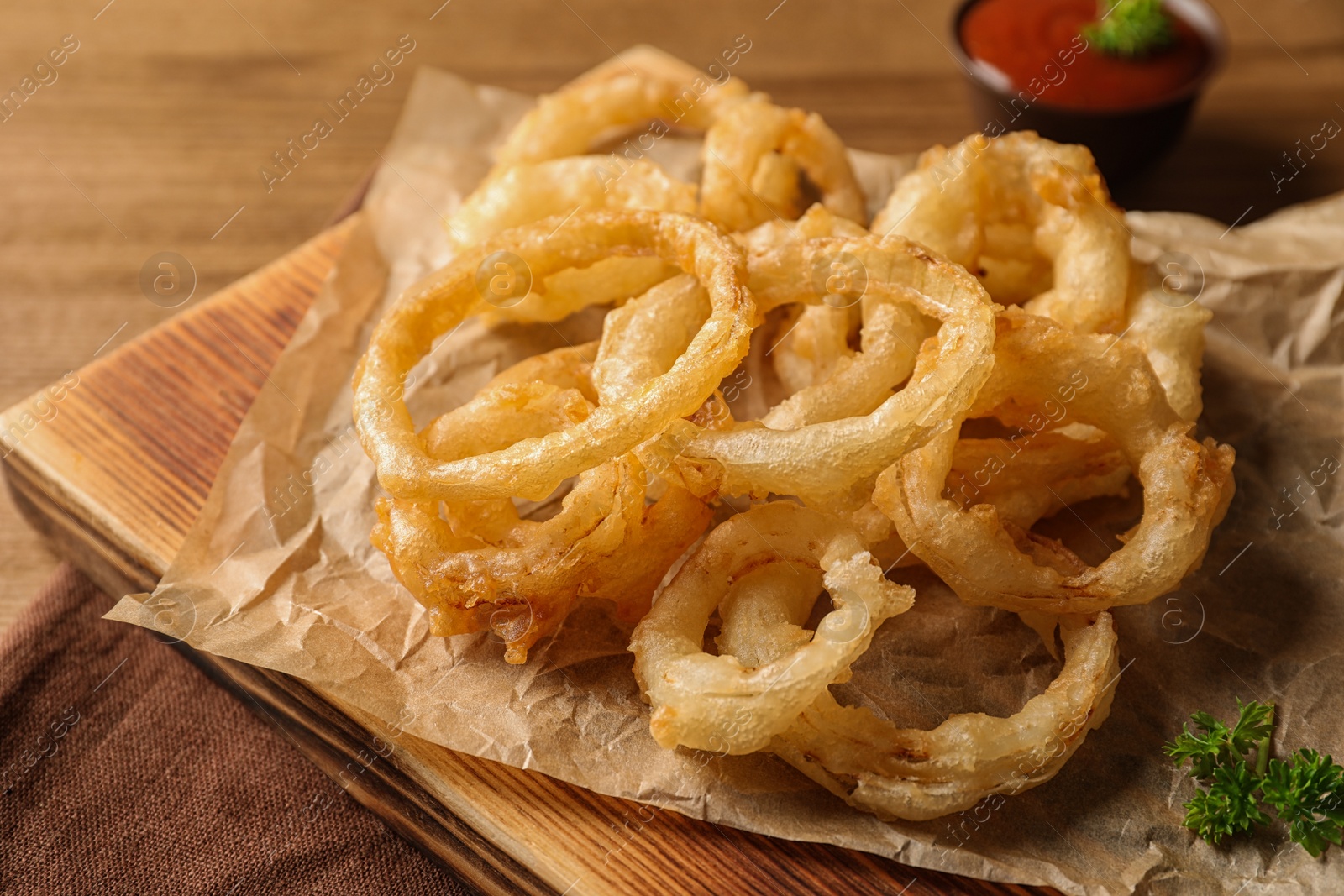 Photo of Homemade delicious golden breaded and deep fried crispy onion rings on wooden background, closeup