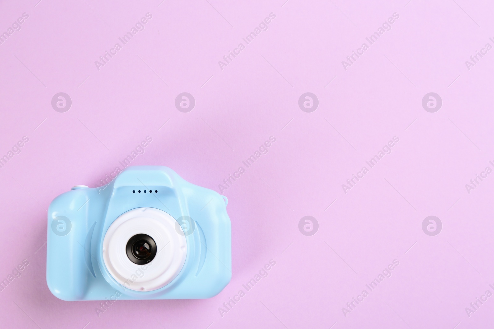 Photo of Light blue toy camera on pink background, top view. Space for text