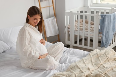 Photo of Happy young pregnant woman in pajamas on bed at home