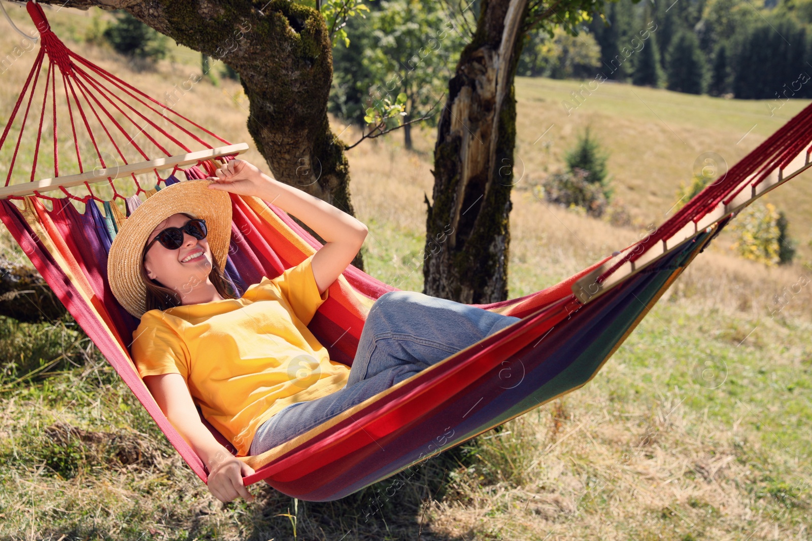 Photo of Young woman resting in hammock outdoors on sunny day