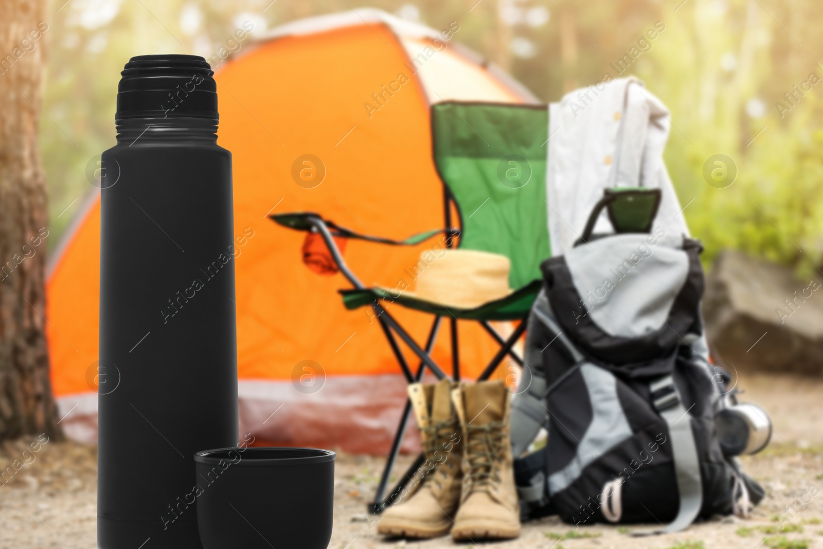 Image of Modern thermos outdoors, space for text. Camping season 