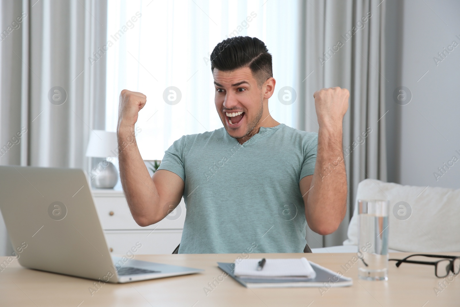 Photo of Emotional man participating in online auction using laptop at home