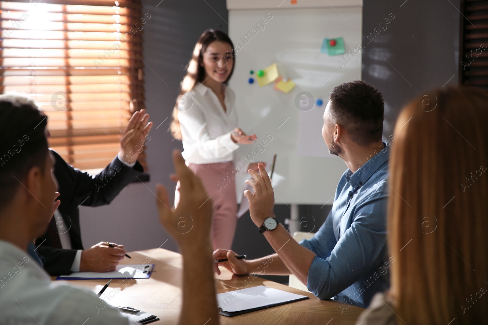 Photo of People raising hands to ask questions at seminar in office