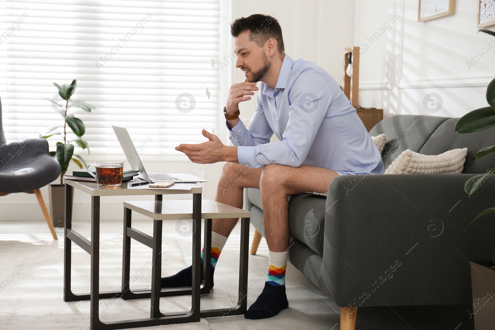 Photo of Businessman in underwear pretending to wear formal clothes during video call at home