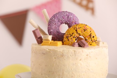 Delicious cake decorated with sweets against blurred background, closeup