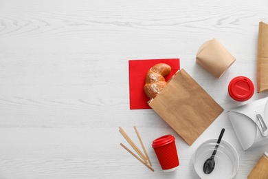 Flat lay composition with paper bag and different takeaway items on wooden background. Space for design