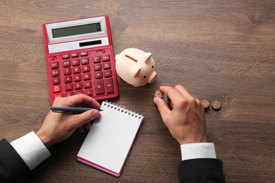 Photo of Budget planning. Businessman with notebook calculating at wooden table, top view