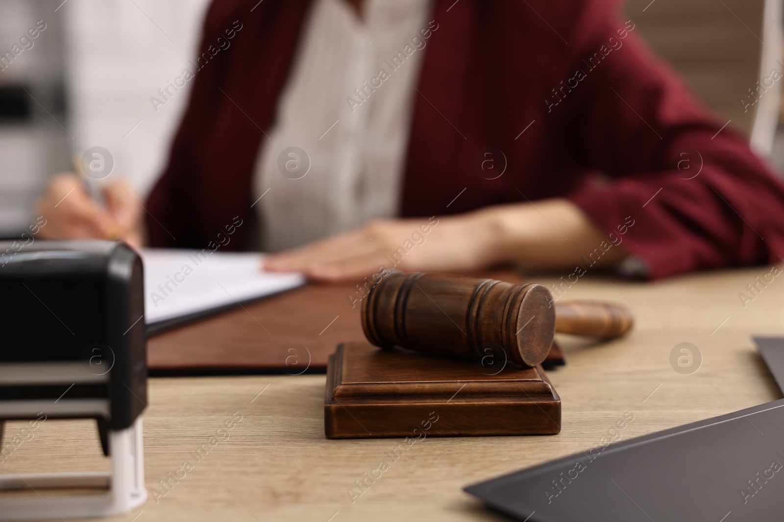 Photo of Notary signing document at wooden table in office, focus on gavel