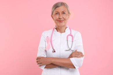 Doctor with pink ribbon and stethoscope on color background. Breast cancer awareness