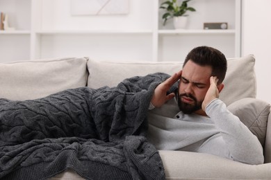 Photo of Man suffering from headache on sofa at home