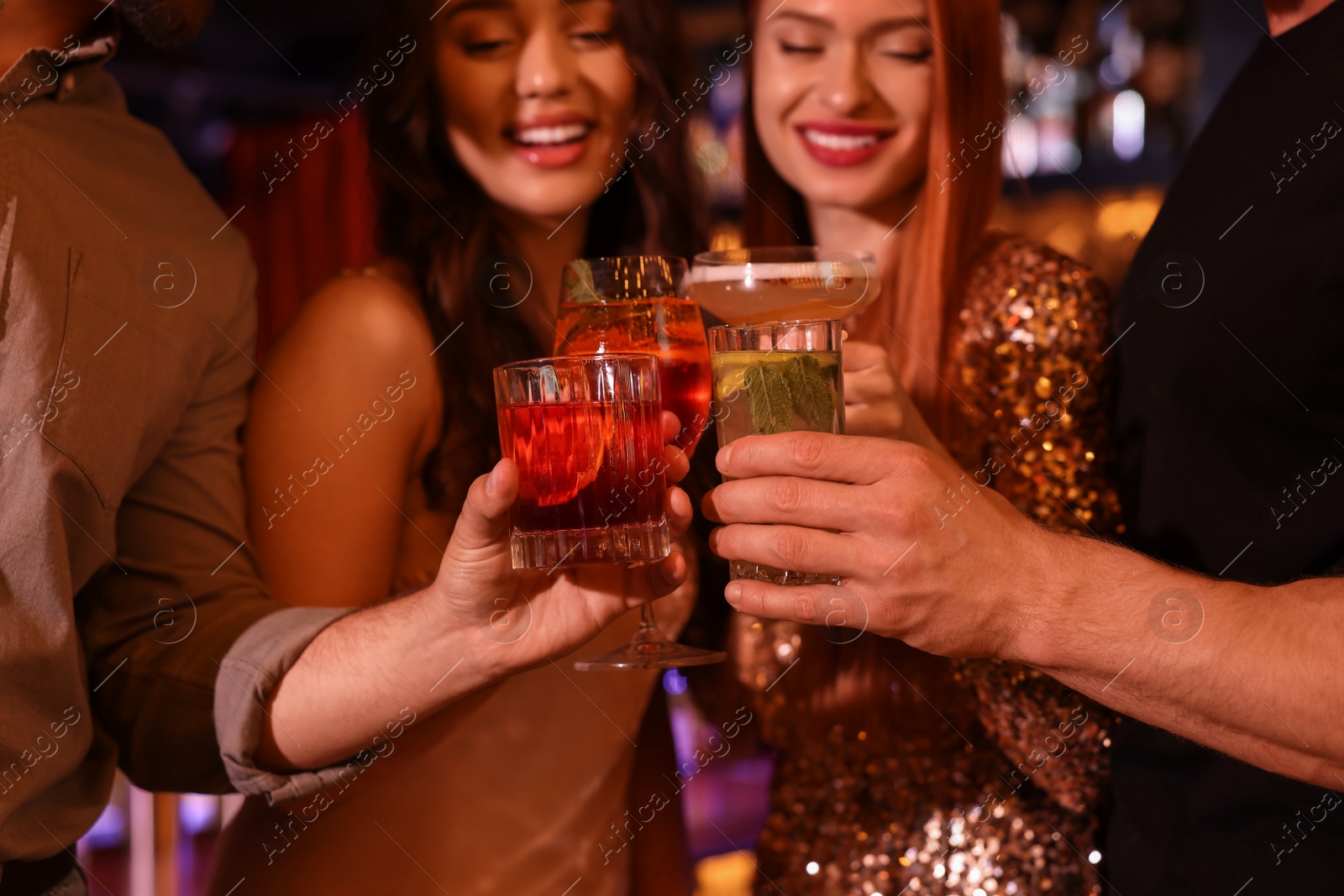 Photo of Friends clinking glasses with fresh cocktails in bar, selective focus