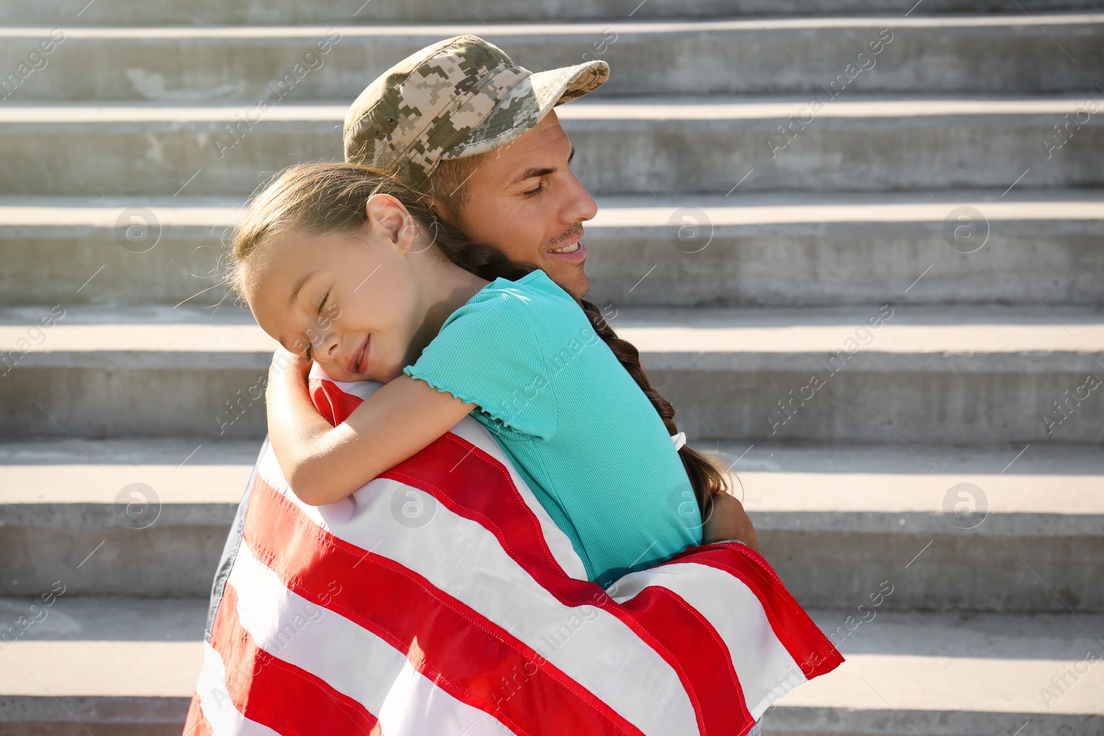 Photo of Soldier with flag of USA and his little daughter hugging outdoors, space for text