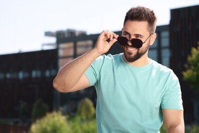 Photo of Handsome smiling man in sunglasses outdoors, space for text