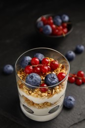 Photo of Delicious yogurt parfait with fresh berries on black table, closeup