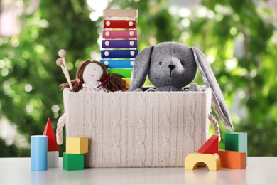 Photo of Box and different toys on table against blurred background