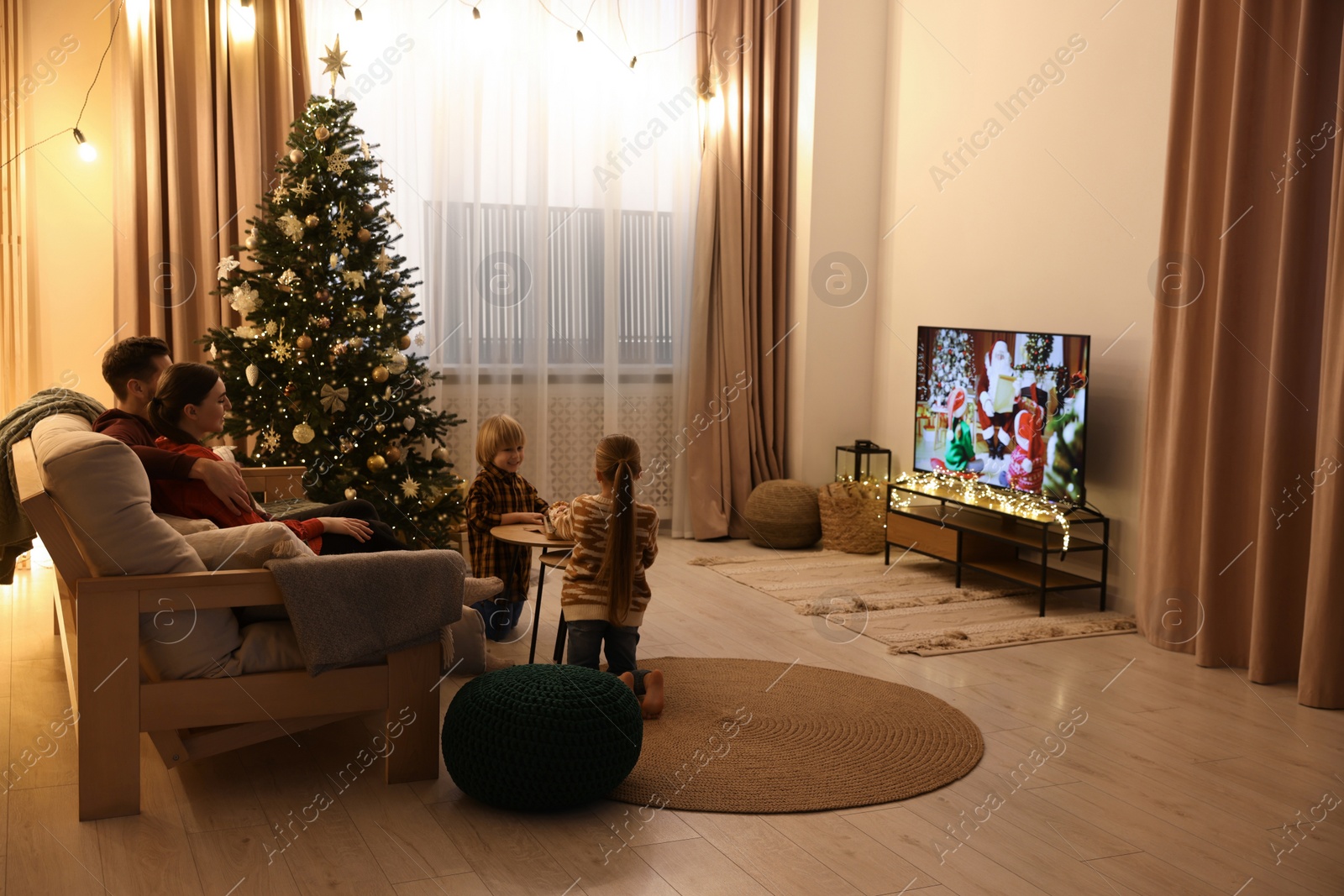 Photo of Family watching TV in cosy room. Christmas atmosphere