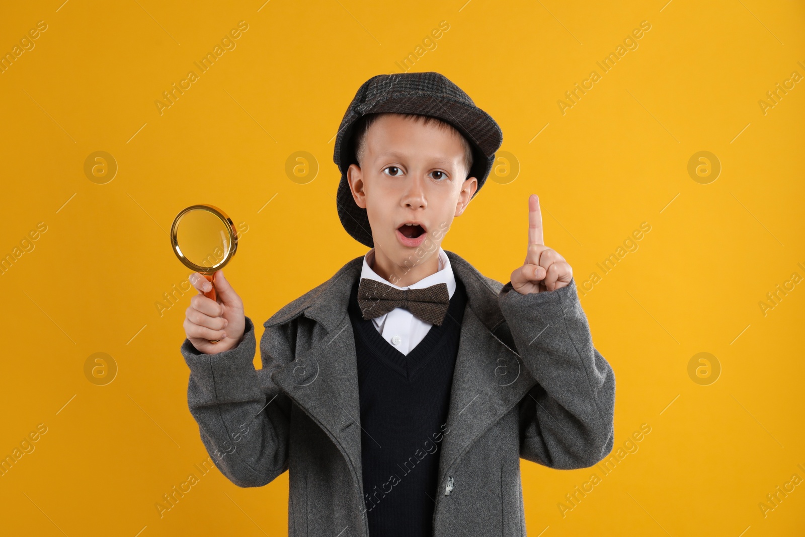 Photo of Cute little detective with magnifying glass on yellow background