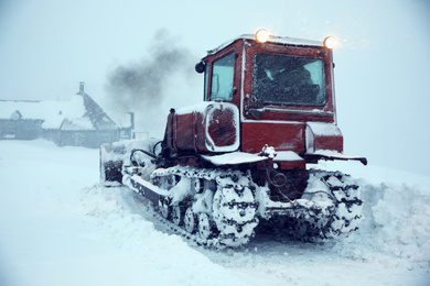 Tractor cleaning road in snowstorm. Winter season