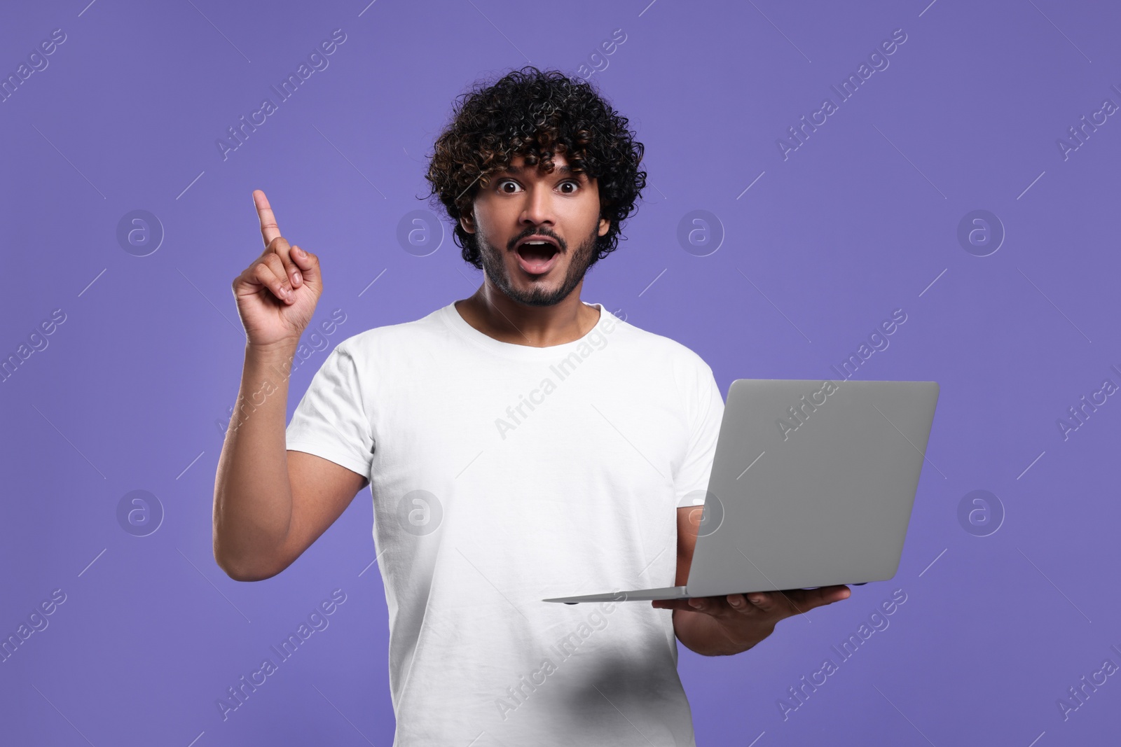 Photo of Surprised man with laptop on purple background