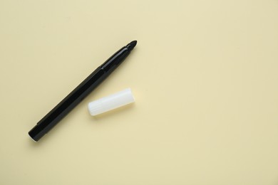 Photo of Black marker and cap on beige background, flat lay. Space for text