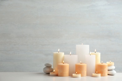 Photo of Beautiful composition with candles on table against light background