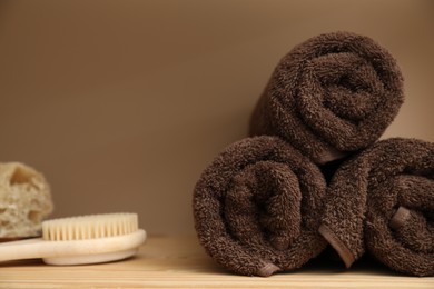Photo of Soft towels and brush on wooden shelf indoors, closeup