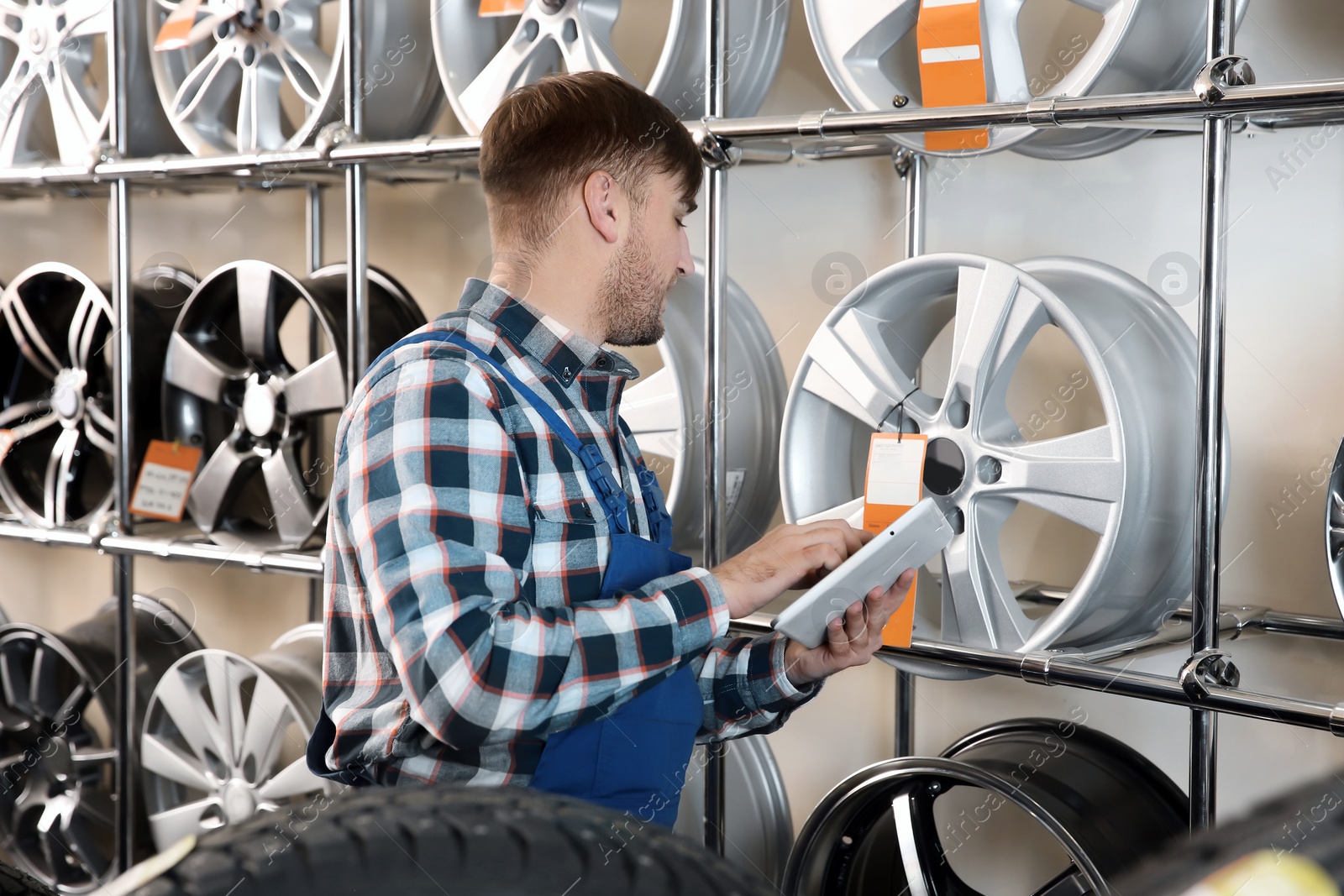 Photo of Young male mechanic with tablet computer in automobile service center