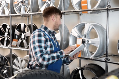 Photo of Young male mechanic with tablet computer in automobile service center