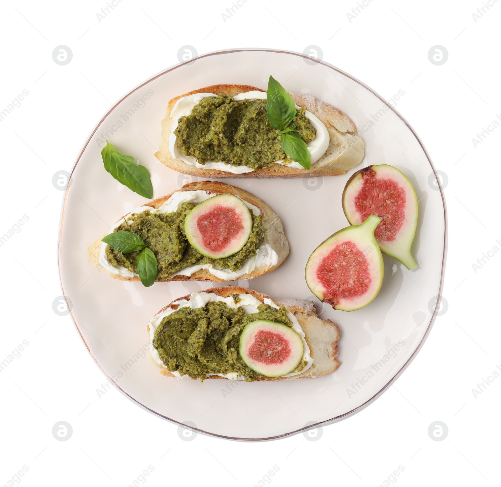 Photo of Plate of tasty bruschettas with cream cheese, pesto sauce, figs and fresh basil isolated on white, top view