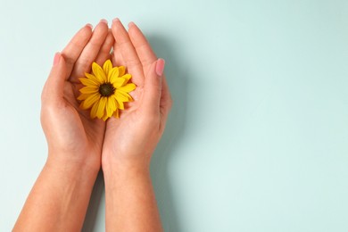 Woman holding beautiful flower on turquoise background, top view. Space for text