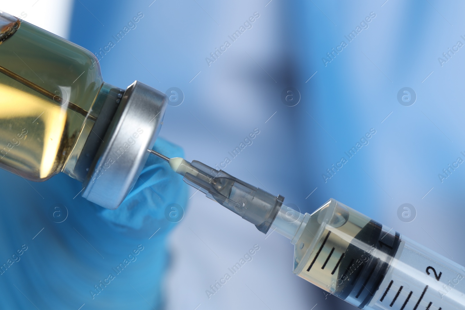 Photo of Doctor filling syringe with medication from glass vial, closeup