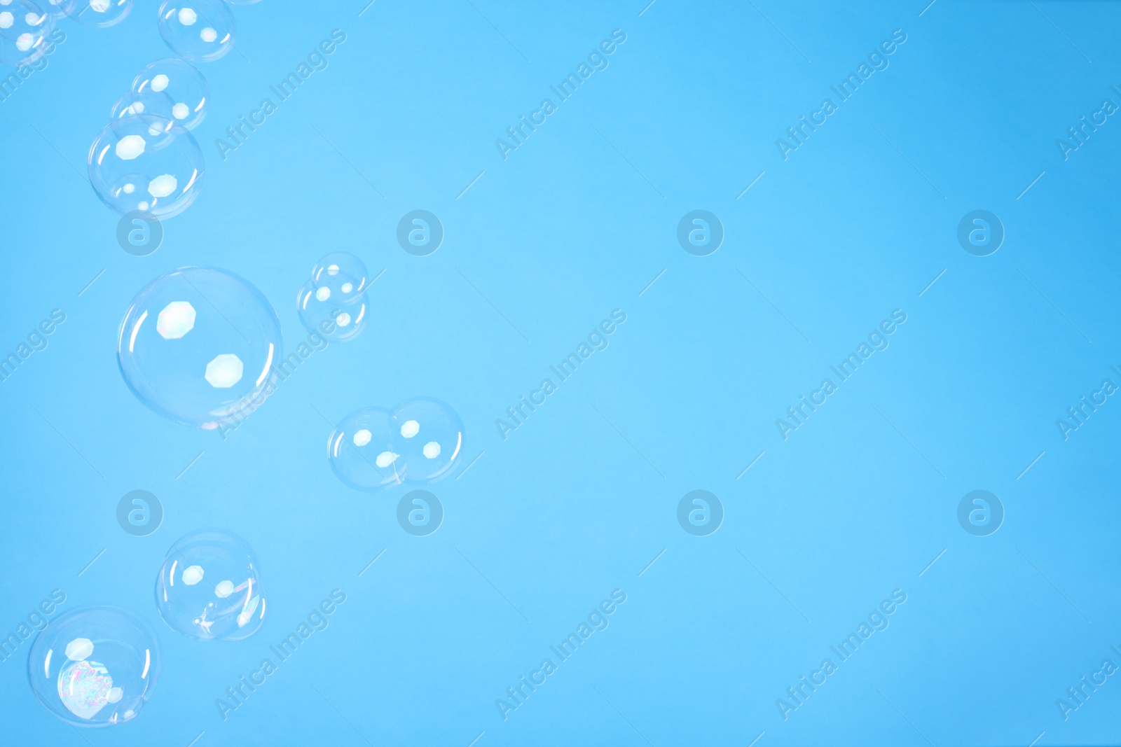 Photo of Many beautiful soap bubbles on light blue background. Space for text