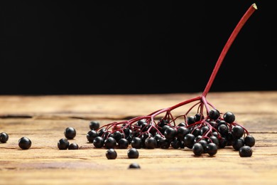 Photo of Elderberries (Sambucus) on wooden table against black background. Space for text