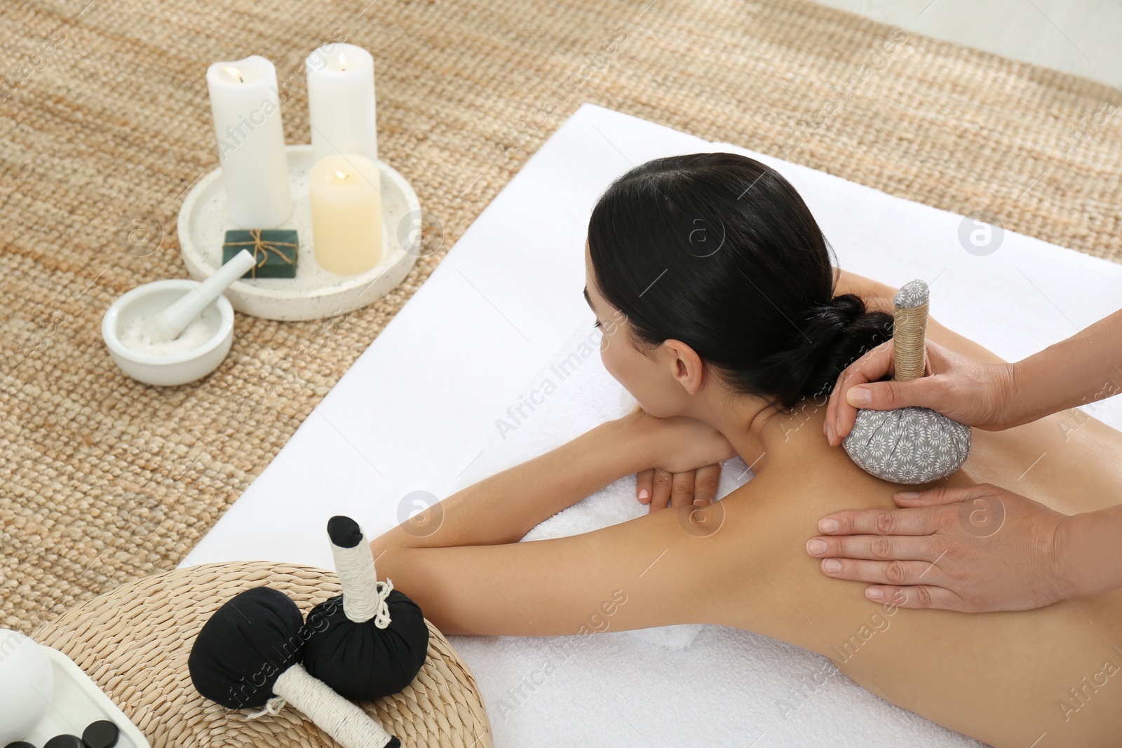 Photo of Young woman receiving herbal bag massage in spa salon