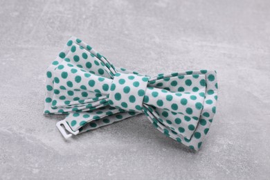 Stylish bow tie with green polka dot pattern on light grey table