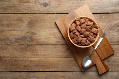 Photo of Sweet crispy corn pads in bowl and spoon on wooden table, flat lay. Space for text