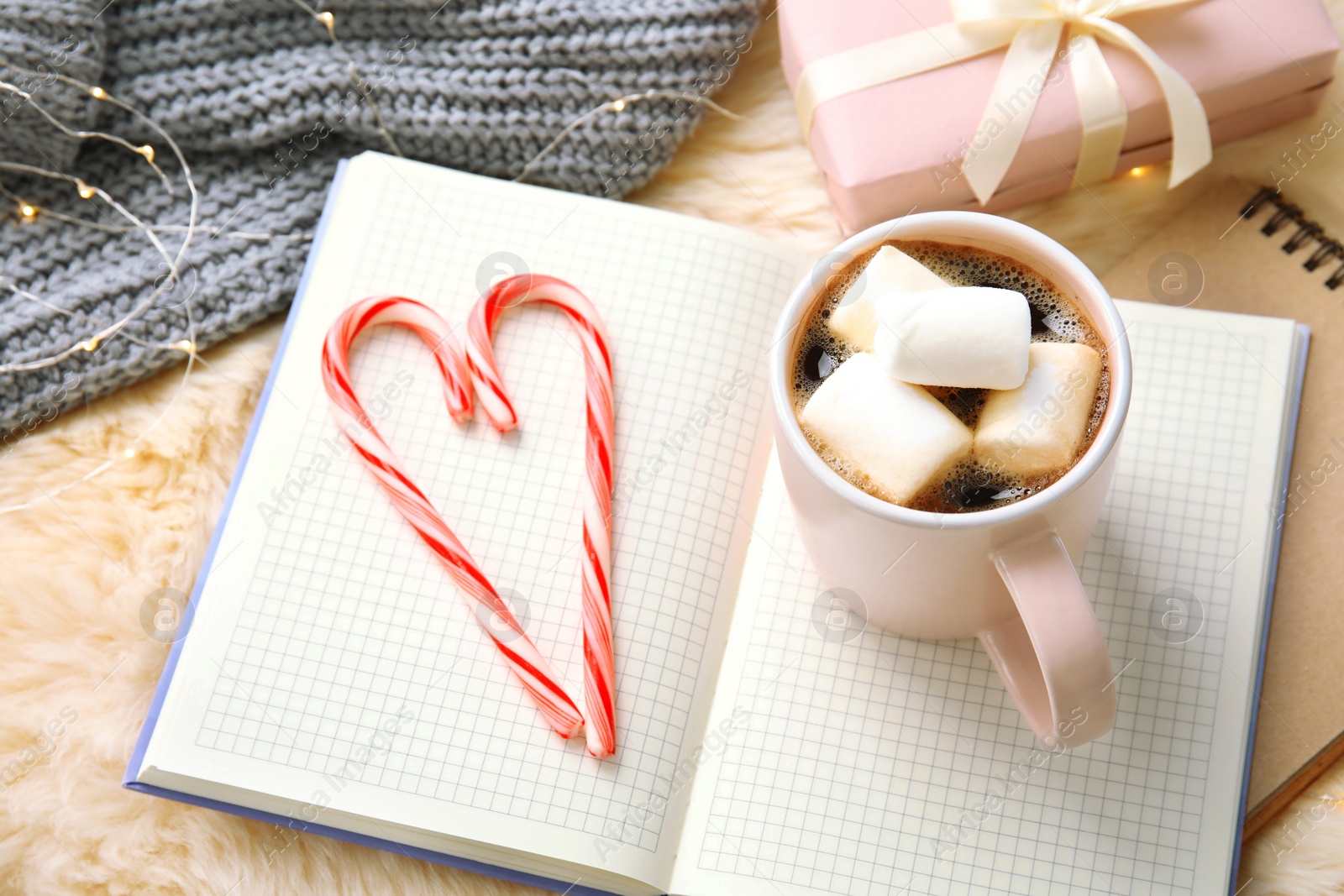 Photo of Composition with cup of hot winter drink and notebooks on fluffy plaid. Cozy season